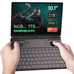 This image shows a GPD Win Max 2 2023, a handheld gaming PC. The screen highlights its key specifications, including a 10.1-inch display with a 2.5K resolution, 16GB of RAM, and 1TB of NVMe storage. It is powered by an AMD Ryzen 5 7640U processor from the Ryzen 7000 series and includes AMD Radeon graphics. The device has built-in gaming controls with joysticks, buttons, and a D-pad, along with a physical QWERTY keyboard for typing. The design suggests it’s tailored for both gaming and productivity, making it a versatile compact device.