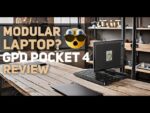 Bild mit einem modularen Laptop, dem GPD Pocket 4, auf einem modernen Holztisch in einem Arbeitsbereich im industriellen Stil. Der überlagerte Text lautet &quot;Modularer Laptop? GPD Pocket 4 Review&quot; mit einem ausdrucksstarken Emoji, das die Überraschung darstellt und das einzigartige modulare Design des Geräts hervorhebt.