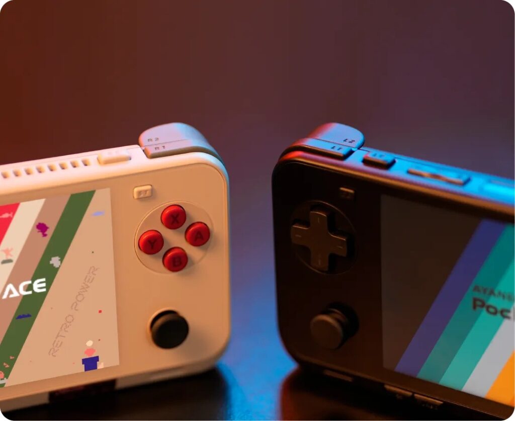 Two AYANEO Pocket ACE handheld gaming consoles side by sideone white with red buttons labeled 'Retro Power', and one black with dark controls. Both display colorful striped screen graphics, showcasing different color schemes. Lit with warm and cool tones to highlight the hardware design and shoulder buttons.