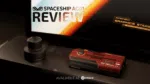 A product review image features a dark red rectangular device possibly a graphics card or mini PC with RX 7600M XT and AYANEO GRAPHICS STARS visible on it In the background a screen displays SPACESHIP AG01 REVIEW with a logo and below the device text reads AVALIABLE AT DROIX A small dark cylindrical object is to the left of the device
