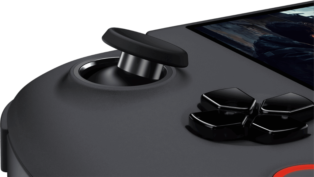 A very close up shot of the left side of a dark grey GPD WIN 5 handheld gaming console The focus is on the left analog stick which is tilted up and away from the device The shiny black D pad is also in focus to the right of the analog stick A small portion of the screen showing a game is visible in the top right